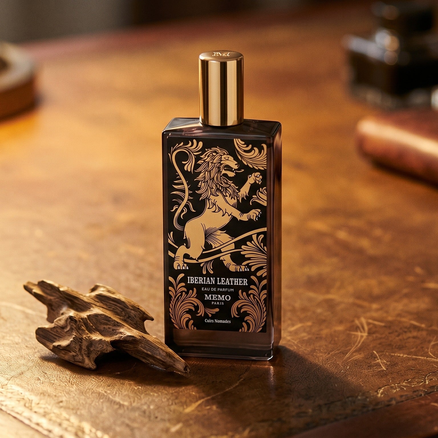 Memo Paris Iberian Leather EDP on aged leather-topped desk with a single agarwood chip beside the bottle