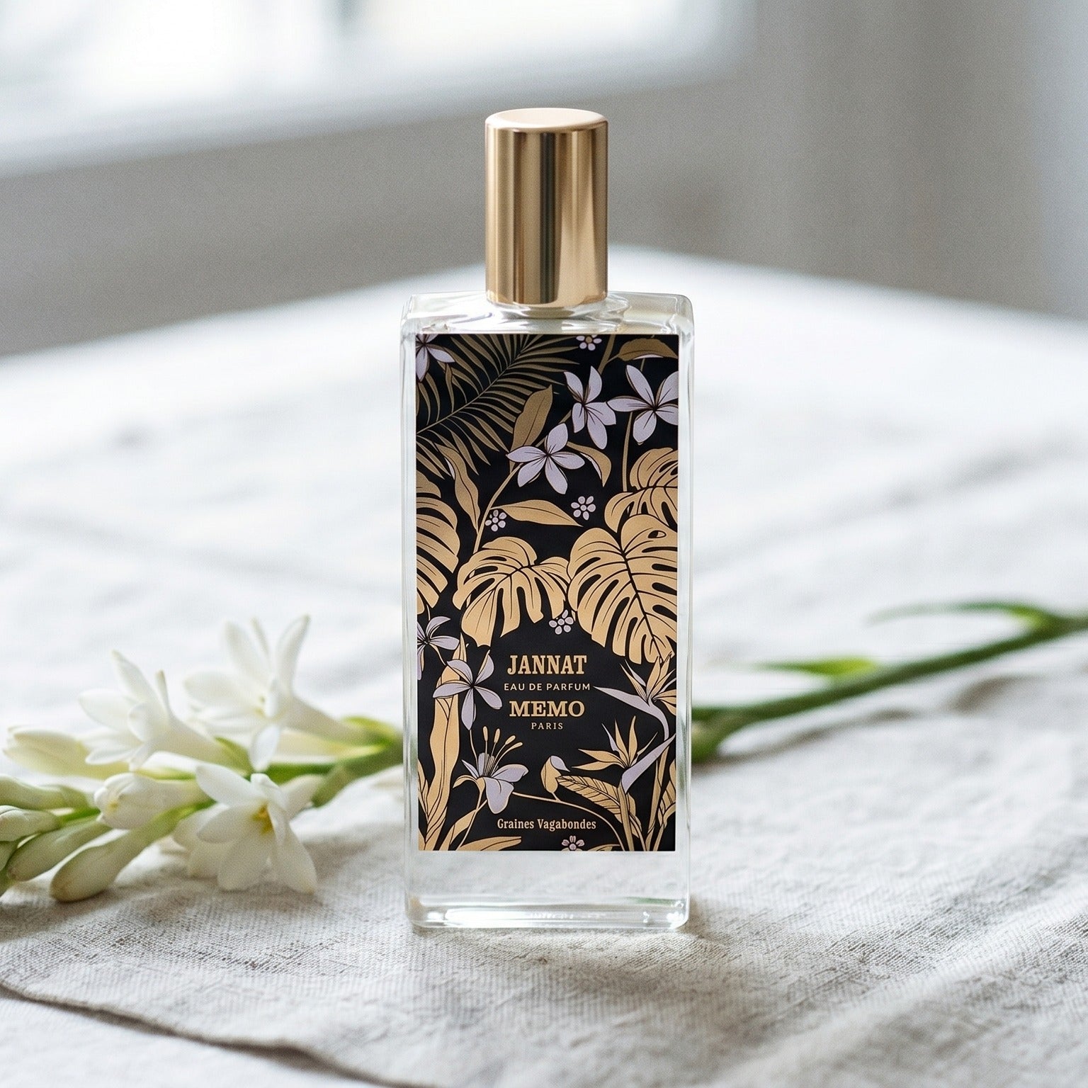 Memo Paris Jannat EDP on bleached linen with a single tuberose stem laid flat