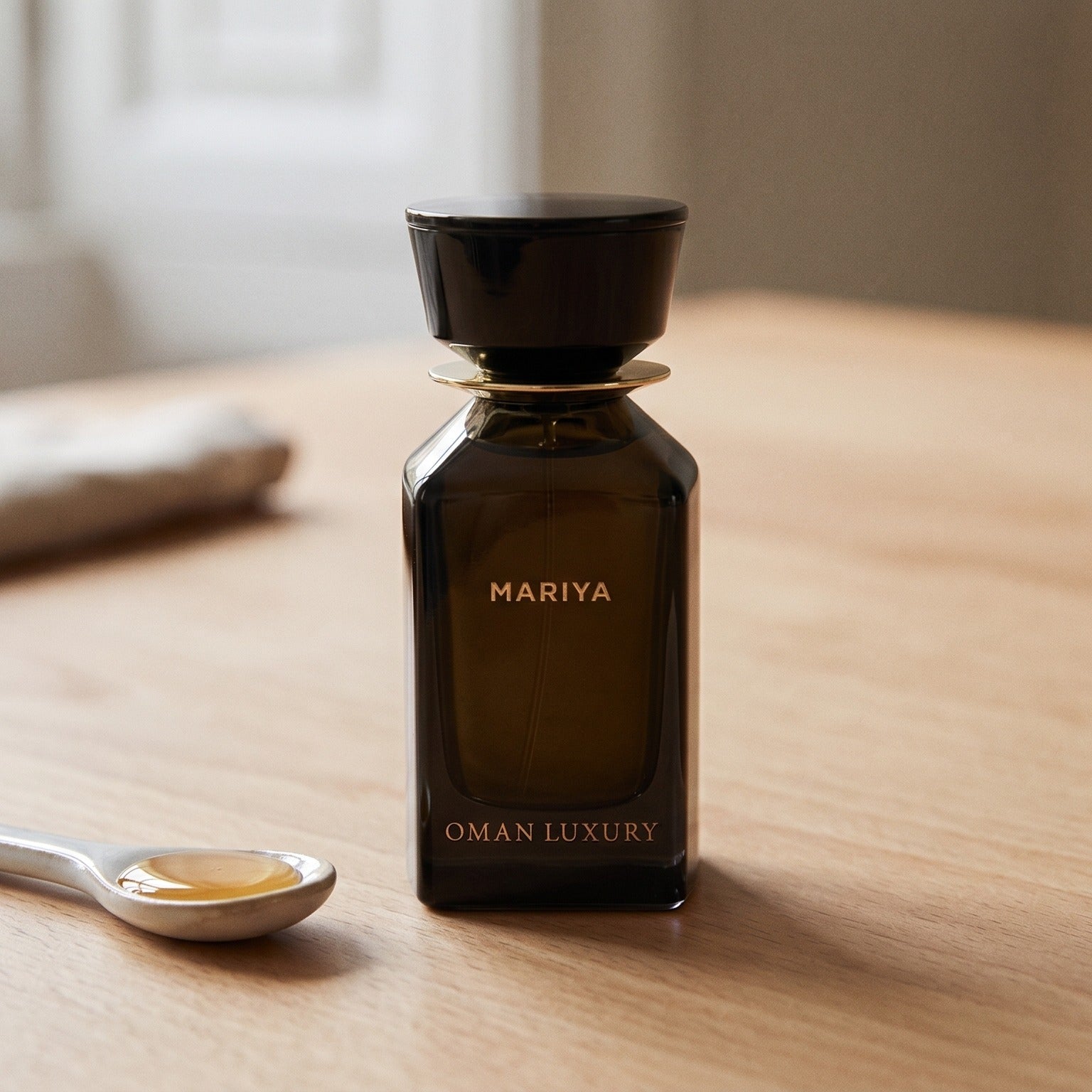 Oman Luxury Mariya EDP on pale beech wood with a small porcelain spoon with honey