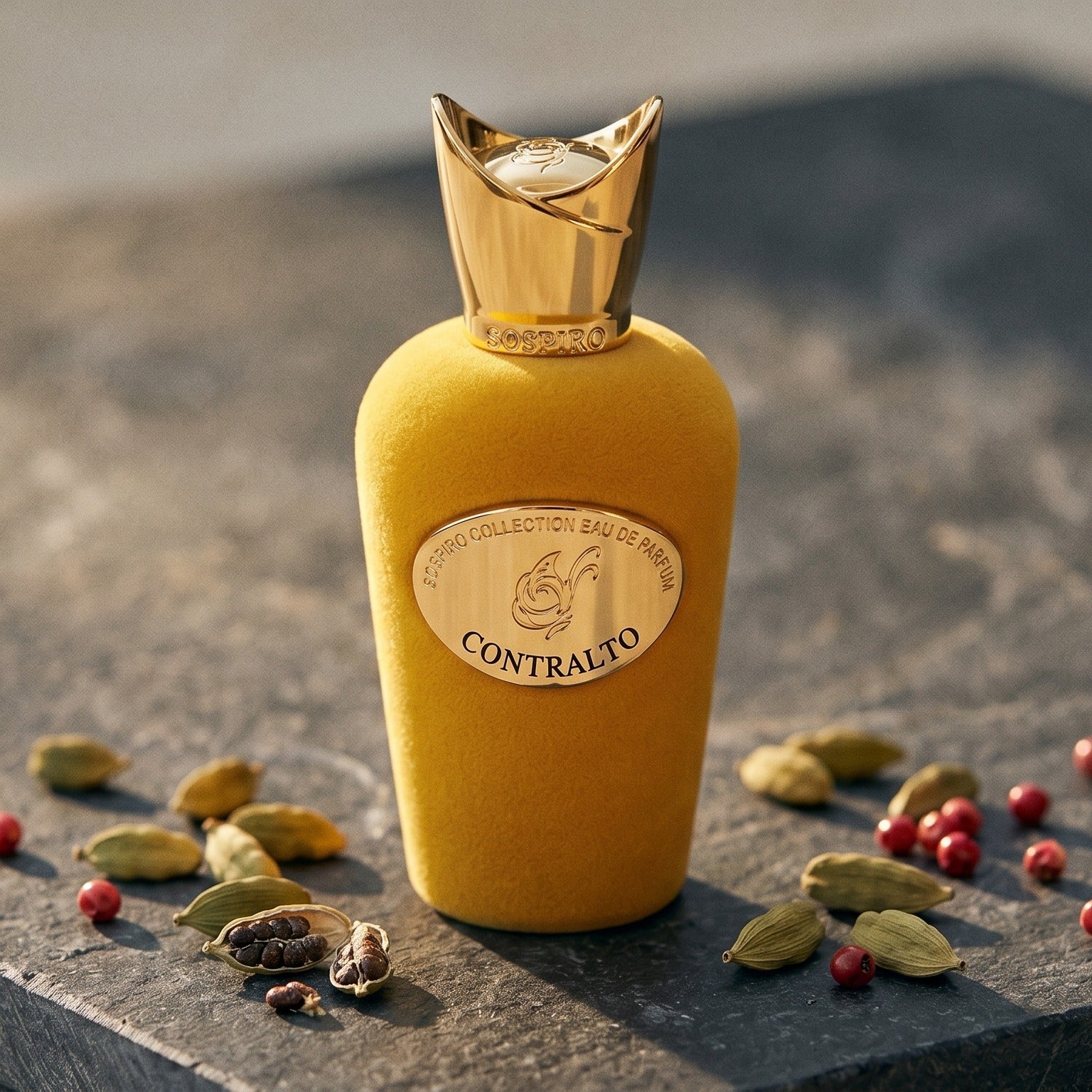Sospiro Contralto EDP on dark grey stone slab with cardamom pods and pink peppercorns scattered