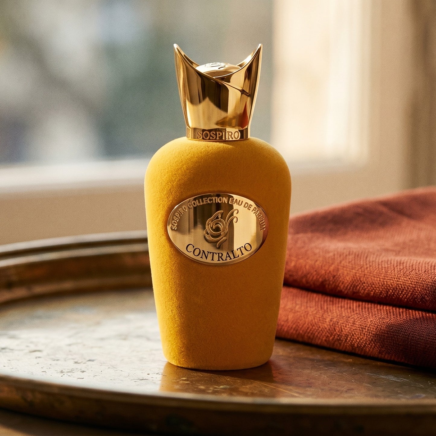 Sospiro Contralto EDP on aged brass tray with a folded pashmina in rust tone