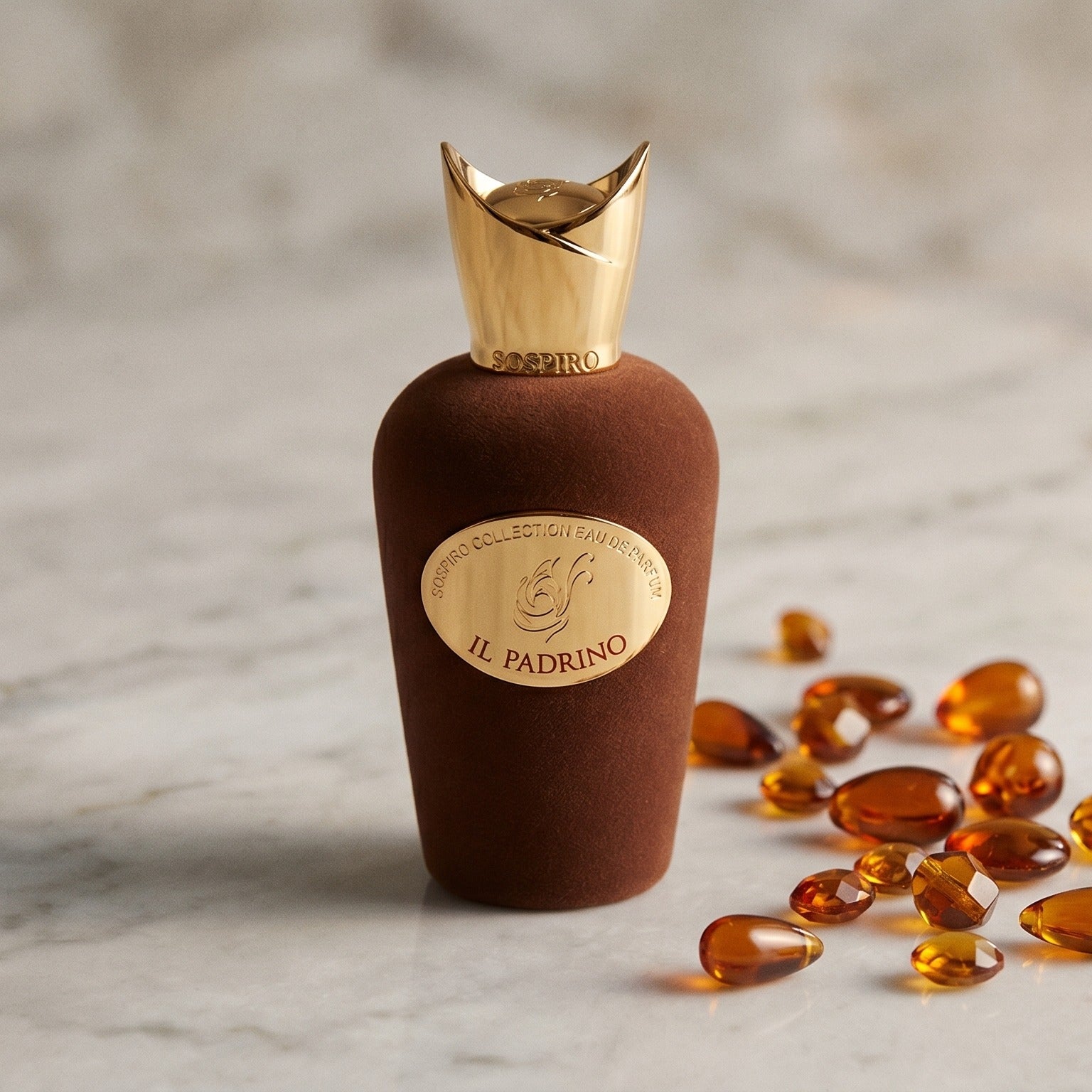 Sospiro IL Padrino EDP on pale grey marble with amber resin beads scattered to one side