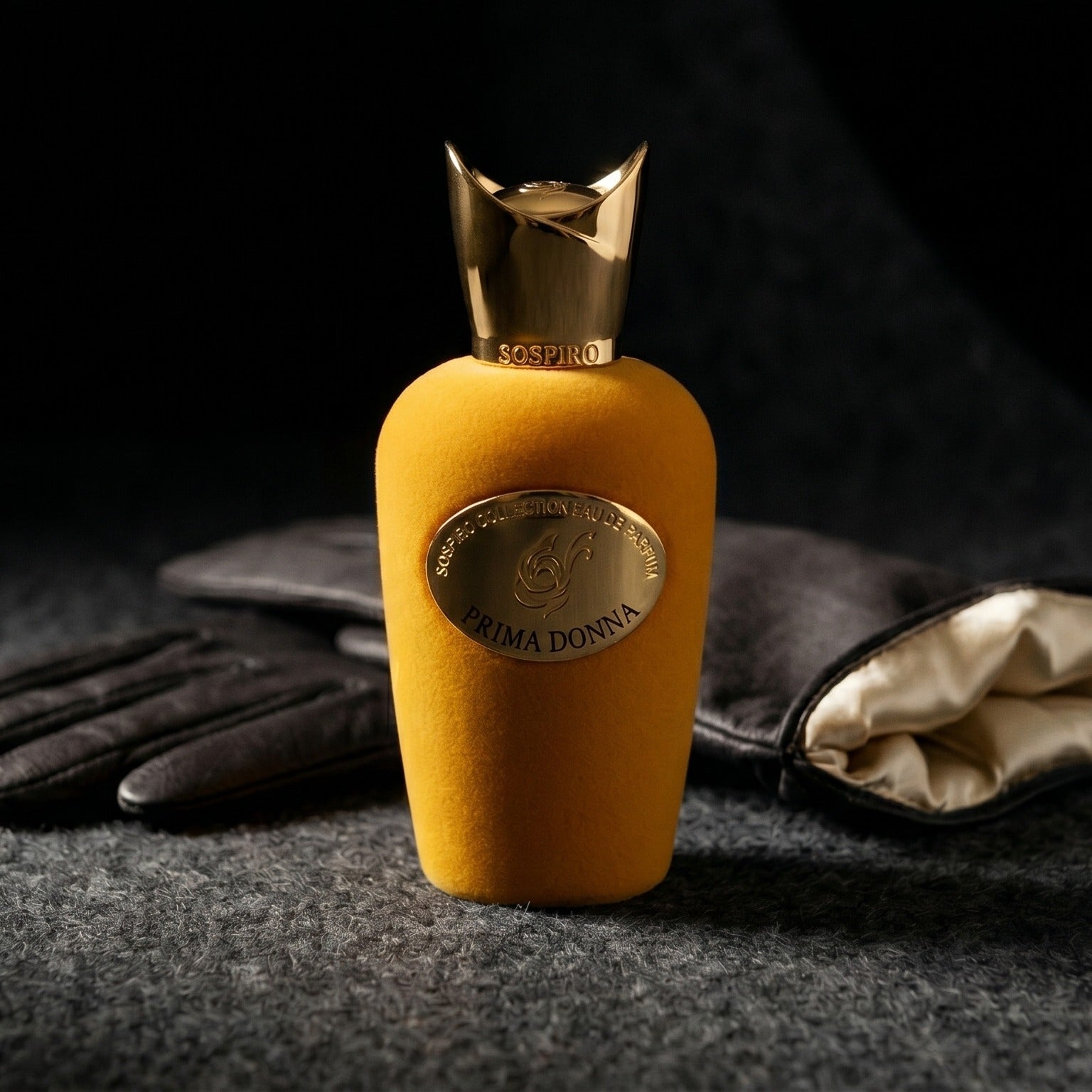 Sospiro Prima Donna EDP on charcoal felt with a silk-lined glove just behind the bottle
