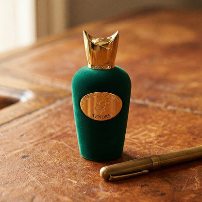 Sospiro Tenore EDP on aged cognac-leather surface with a brass fountain pen resting beside the bottle