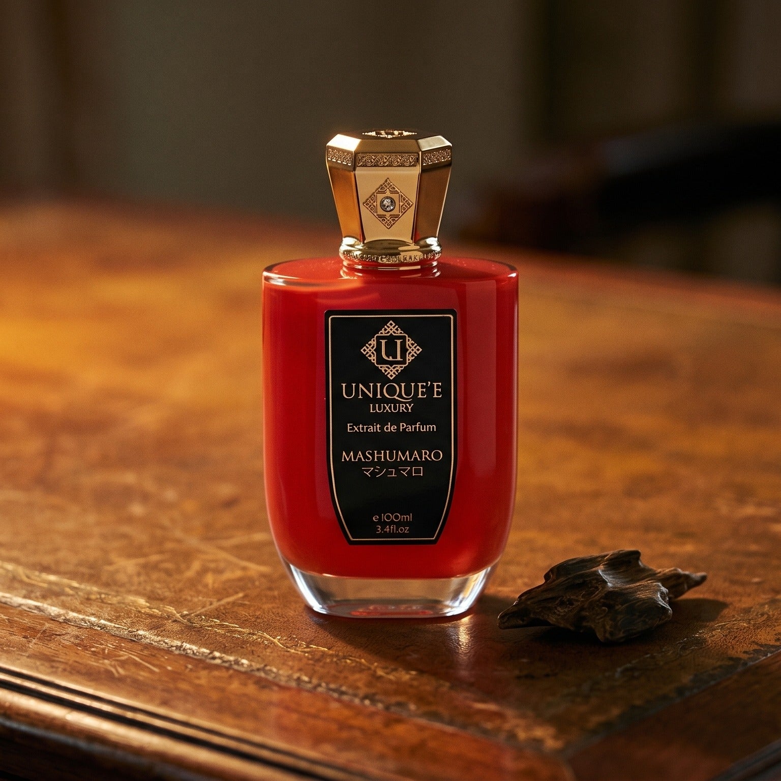 Unique Luxury Mashumaro Extrait on aged leather-topped desk with a single agarwood chip beside the bottle