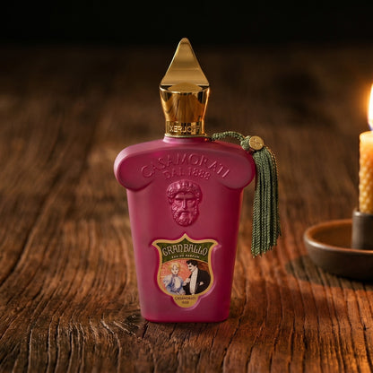 Xerjoff Gran Ballo EDP on aged teak with a candle burning gently to frame-right