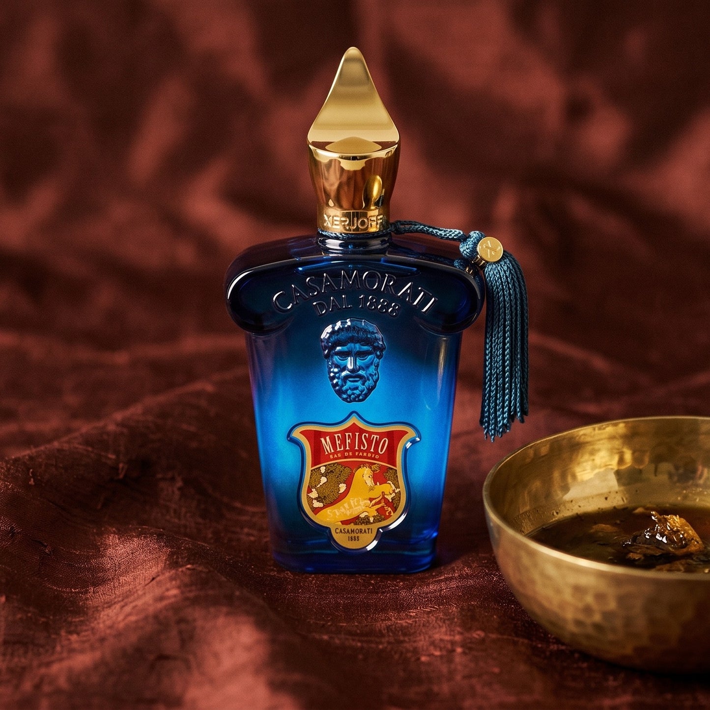 Xerjoff Mefisto EDP on raw silk of oxblood color with a brass bowl with ambergris tincture
