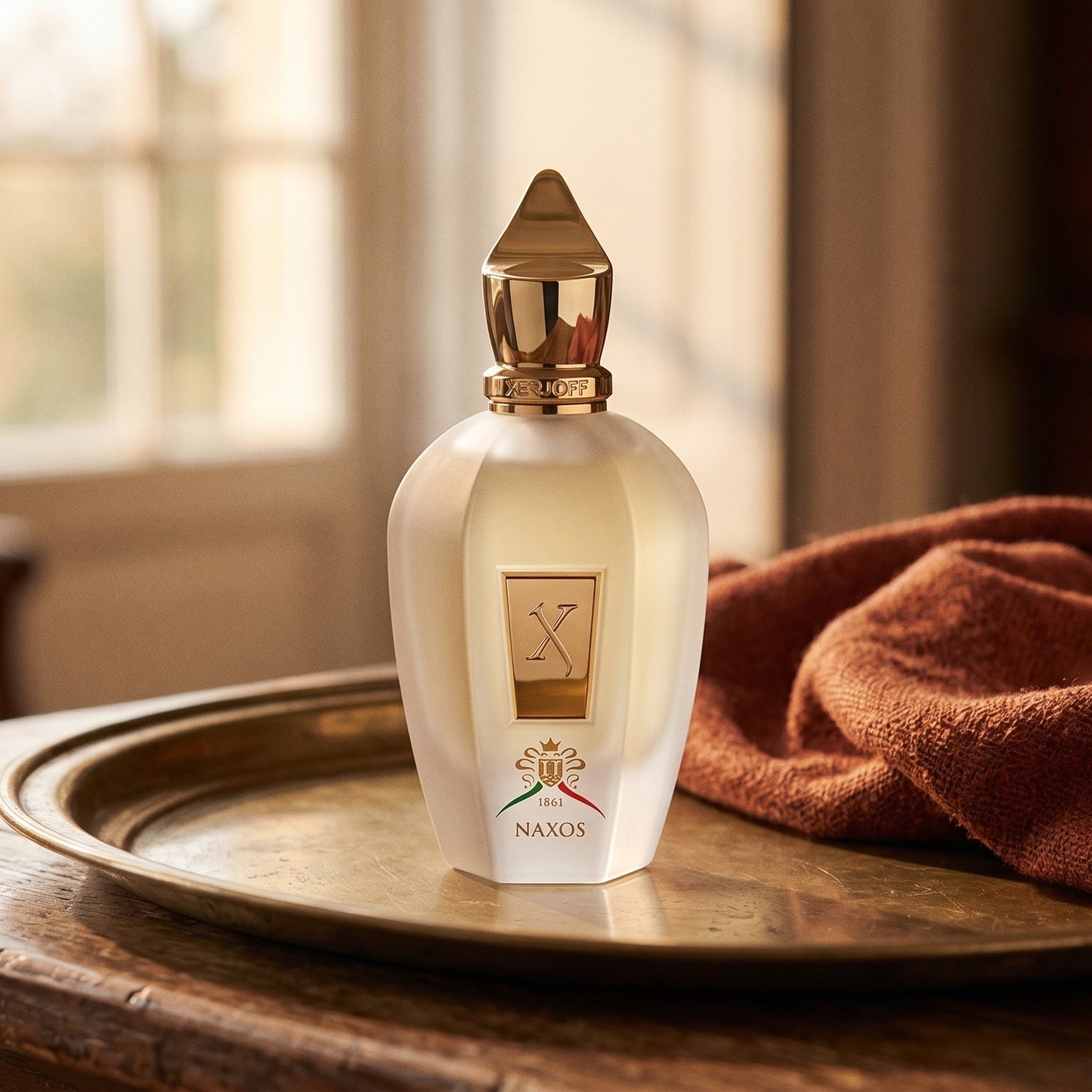 Xerjoff Naxos EDP on aged brass tray with a folded pashmina in rust tone