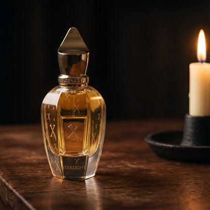 Xerjoff Starlight Parfum on aged teak with a candle burning gently to frame-right