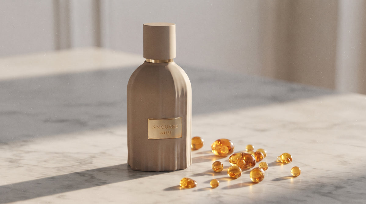Amouage Lustre Essence de Parfum on pale grey marble with amber resin beads scattered to one side