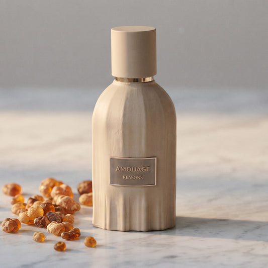 Amouage Reasons Essence de Parfum on pale grey marble with amber resin beads scattered to one side