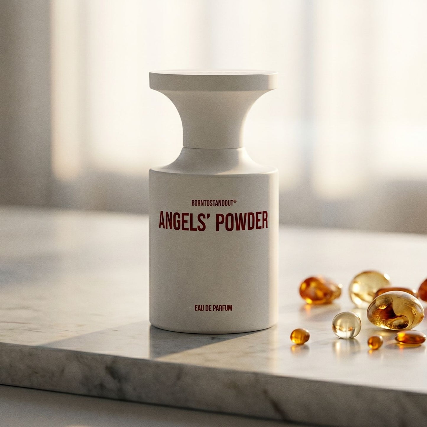 Borntostandout Angels EDP on cream stone with a scatter of honey-colored ambergris flakes