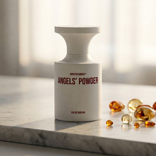 Borntostandout Angels EDP on cream stone with a scatter of honey-colored ambergris flakes