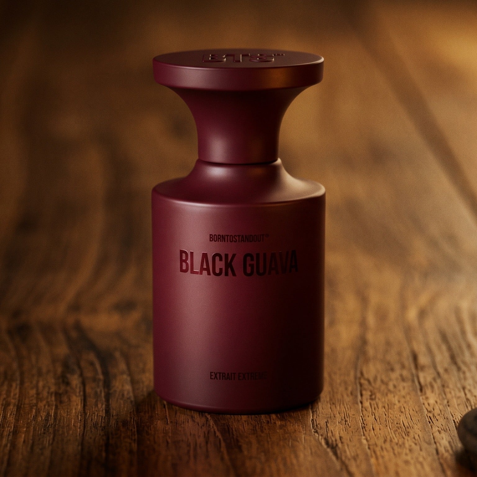 Borntostandout Black Guava Extrait Extreme on walnut side table with a pair of lit votives beside the bottle