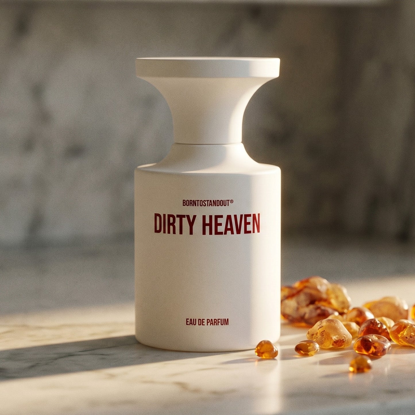 Borntostandout Dirty Heaven EDP on cream stone with a scatter of honey-colored ambergris flakes