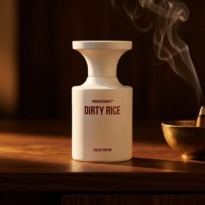 Borntostandout Dirty Rice EDP on dark walnut console with a small brass incense bowl, smoke curling upward