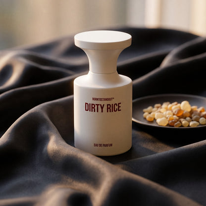 Borntostandout Dirty Rice EDP on burnt-orange silk with smoldering agarwood on a stone dish