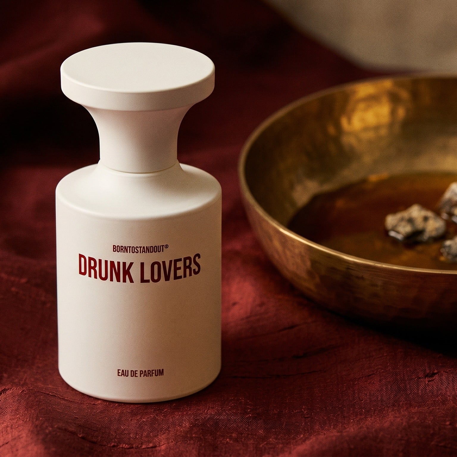 Borntostandout Drunk Lovers EDP on burnt-orange raw silk with a brass vial of frankincense oil