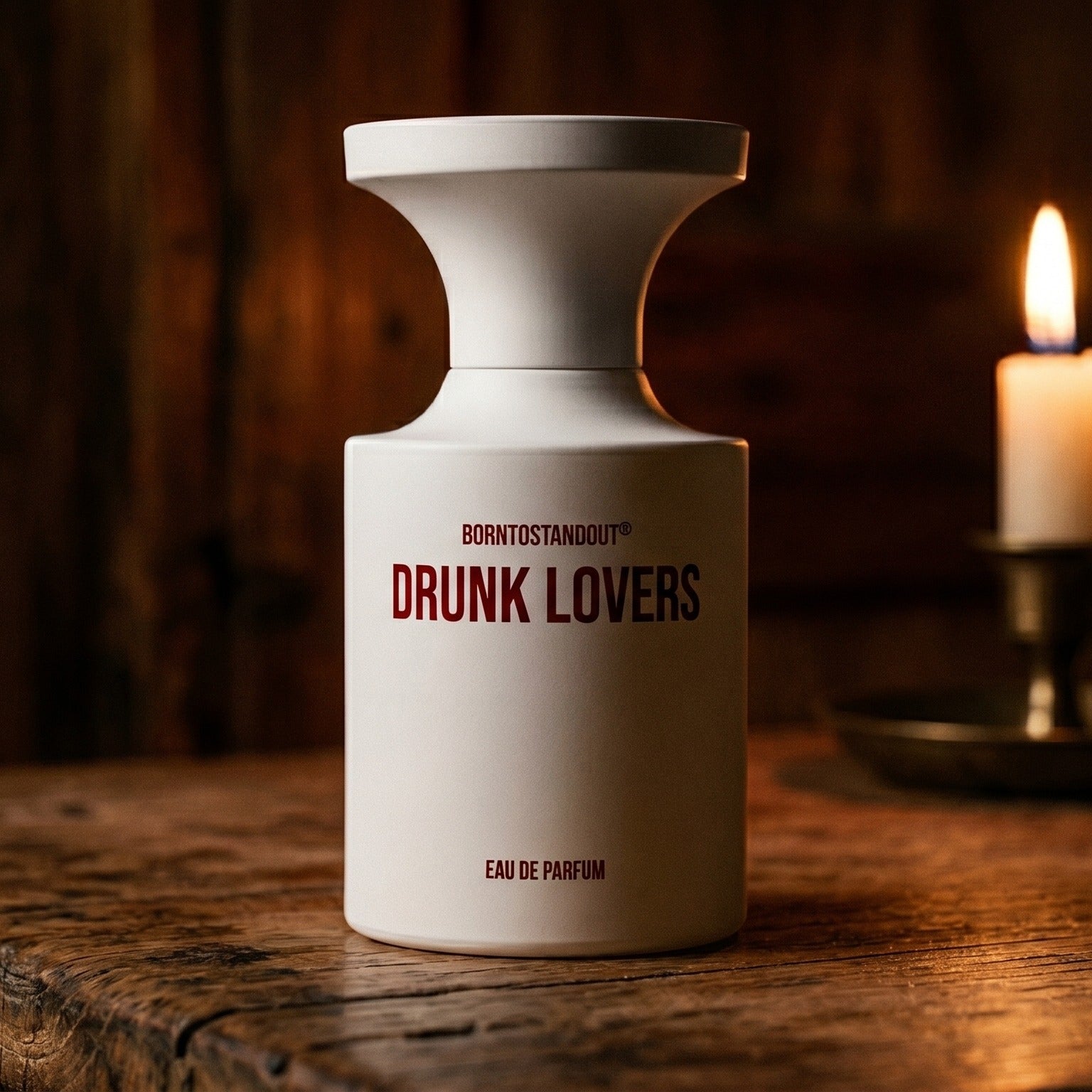 Borntostandout Drunk Lovers EDP on walnut side table with a pair of lit votives beside the bottle