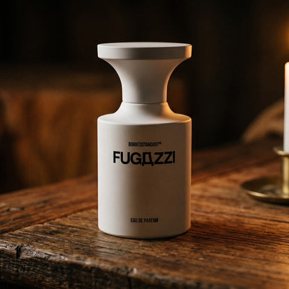 Borntostandout Fugazzi By EDP on rosewood surface with a squat brass candle flickering nearby