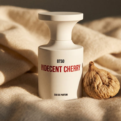 Borntostandout Indecent Cherry EDP on beige wool with a halved dried date and a few almonds