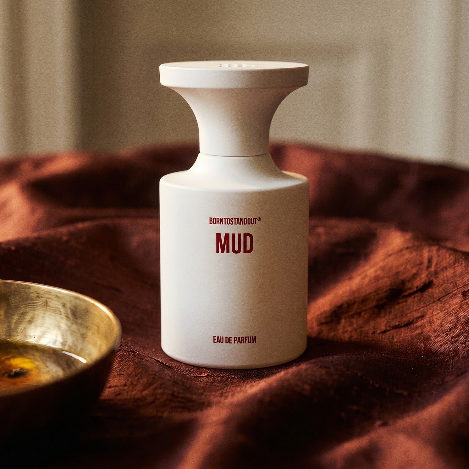 Borntostandout Mud EDP on deep caramel velvet with a small copper jar of resin balm