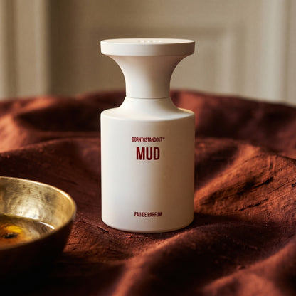 Borntostandout Mud EDP on deep caramel velvet with a small copper jar of resin balm