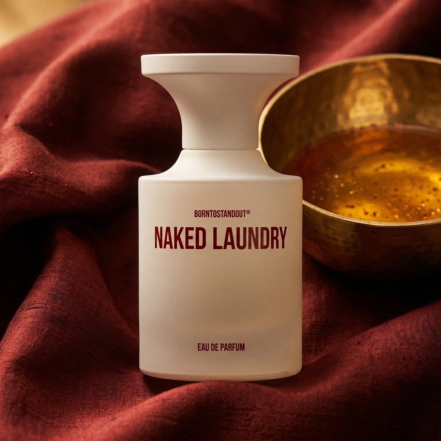 Borntostandout Naked Laundry EDP on raw silk of oxblood color with a brass bowl of ambergris tincture