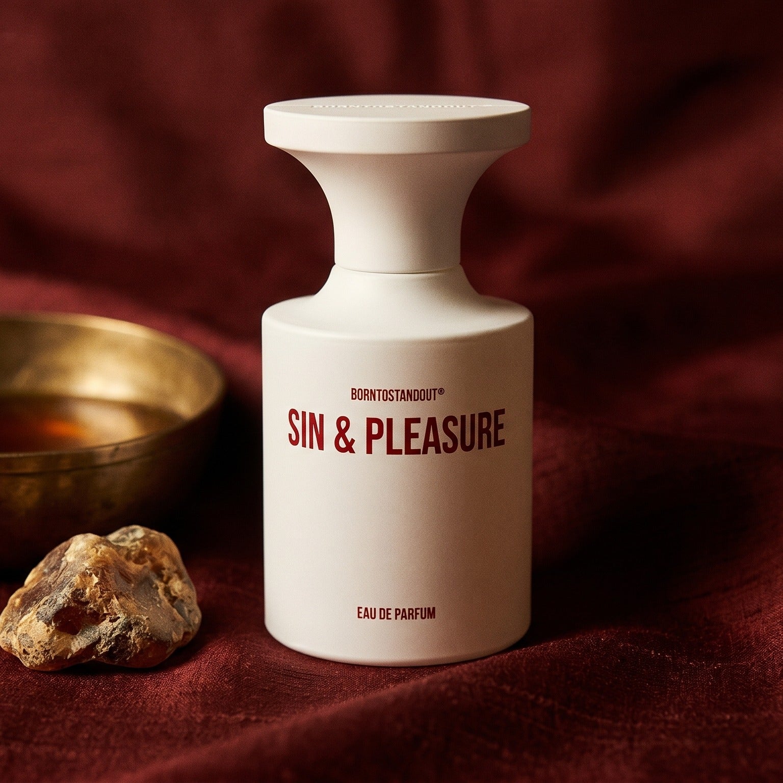 Borntostandout Sin & Pleasure EDP on burnt-orange raw silk with a brass vial of frankincense oil