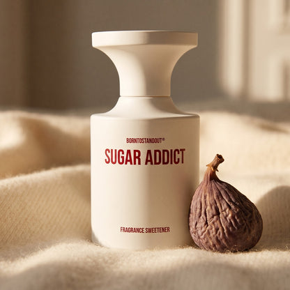 Borntostandout Sugar Addict EDP on cream cashmere with a single dried fig placed beside the bottle