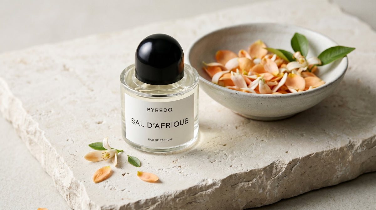 Byredo Bal'd Afrique on pale stone with orange-blossom petals in a shallow bowl