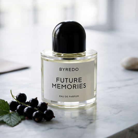 Byredo Future Memories EDP on pale grey marble with a small cluster of blackcurrants with green leaves