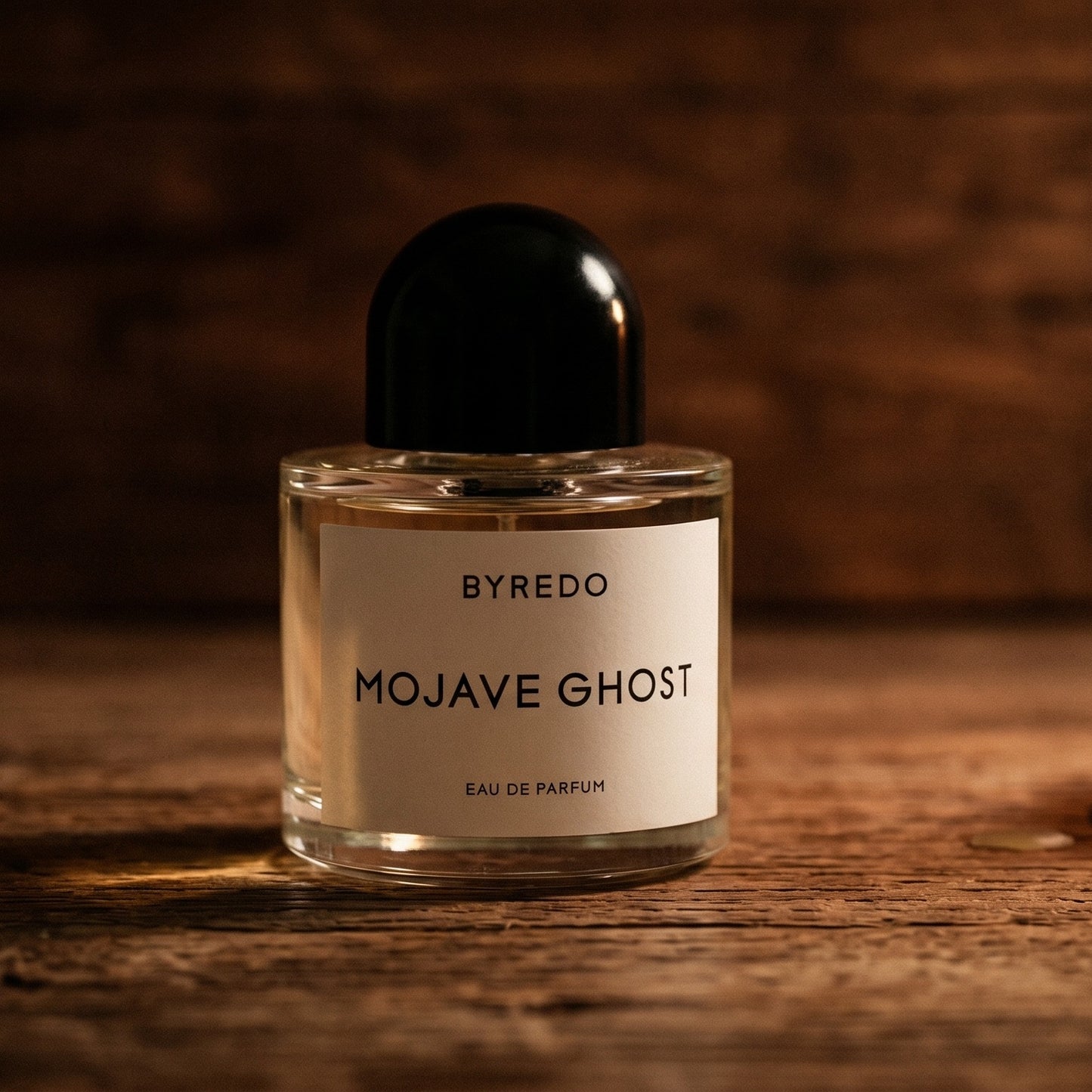 Byredo Mojave Ghost on aged maple with a slender candlestick and drifting smoke