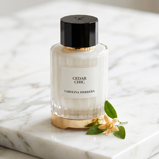 Carolina Herrera Cedar Chic EDP on white carrara marble with a sprig of orange blossom