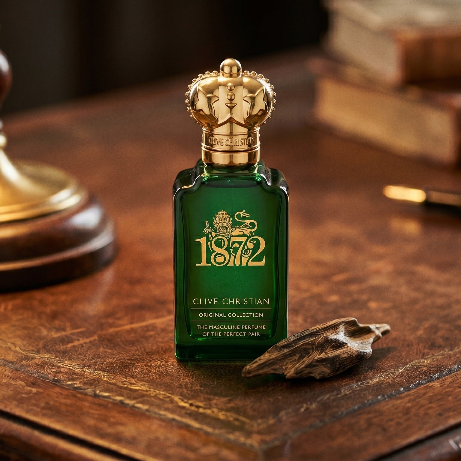Clive Christian 1872 Masculin on aged leather-topped desk with a single agarwood chip beside the bottle