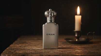 Clive Christian Kinam Parfum - Dubai Exclusive on aged teak with a candle burning gently to frame-right