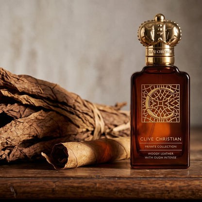 Clive Christian Private Collection C Woody Leather Oud on aged walnut console with a loose bundle of dried tobacco leaves