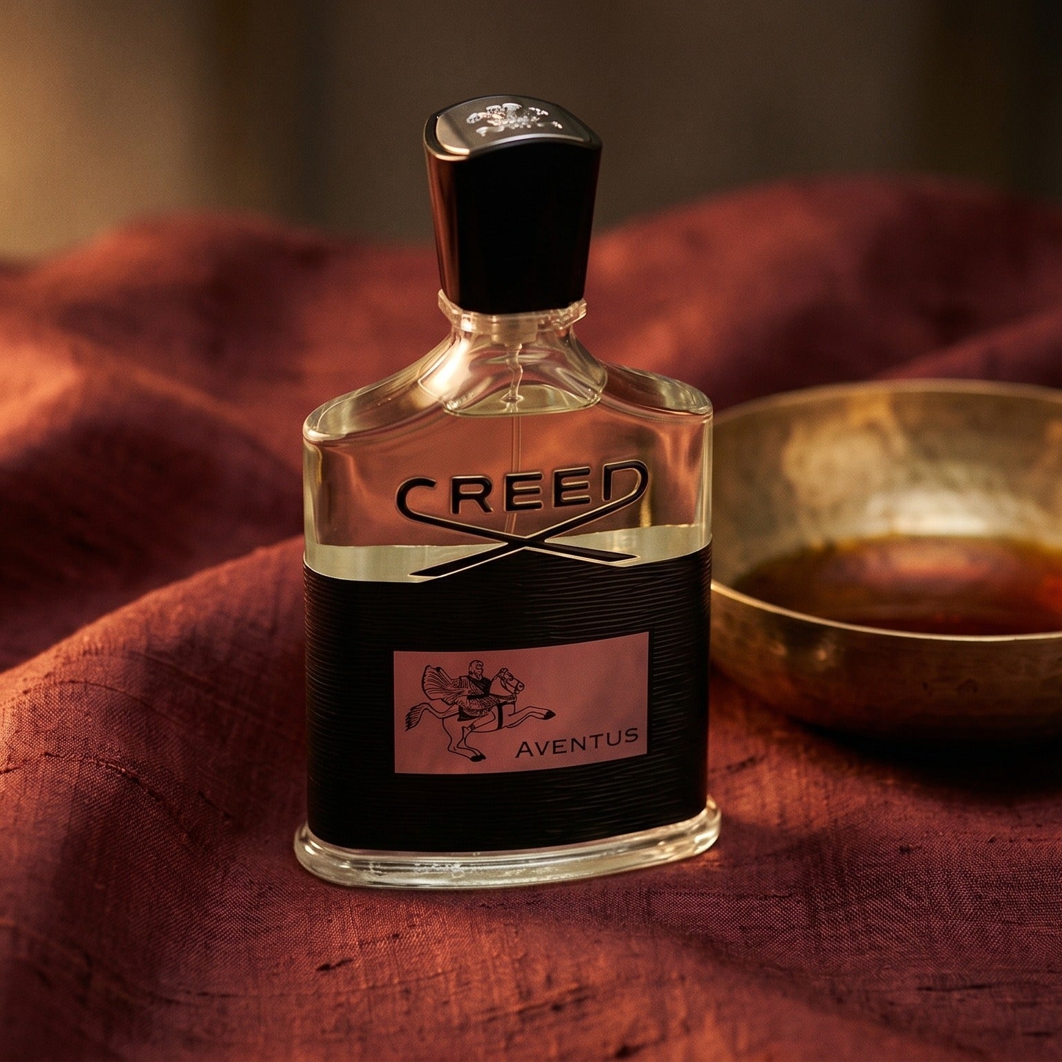 Creed Aventus on raw silk of oxblood color with a brass bowl with ambergris tincture