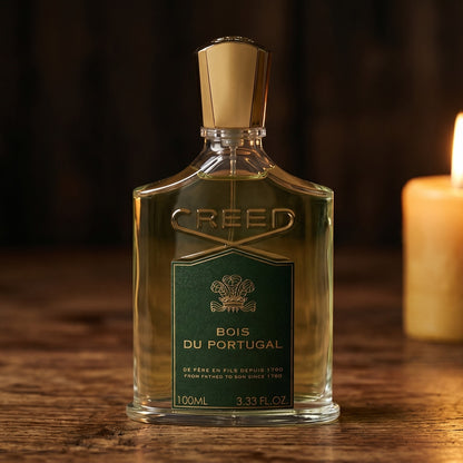 Creed Bois de Portugal on reclaimed oak surface with a glass hurricane lamp softly glowing