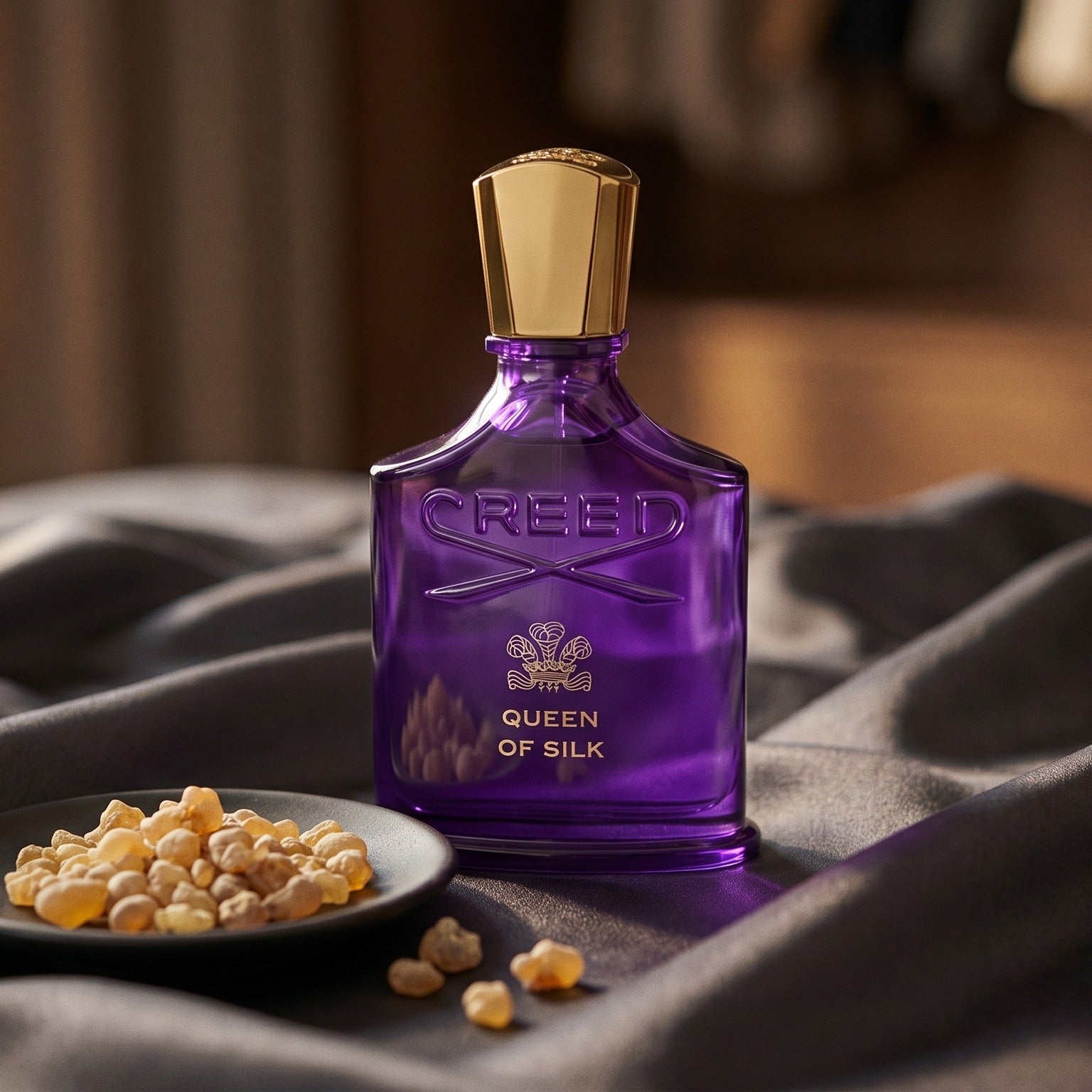 Creed Queen of Silk EDP on burnt-orange silk with smoldering agarwood on a stone dish