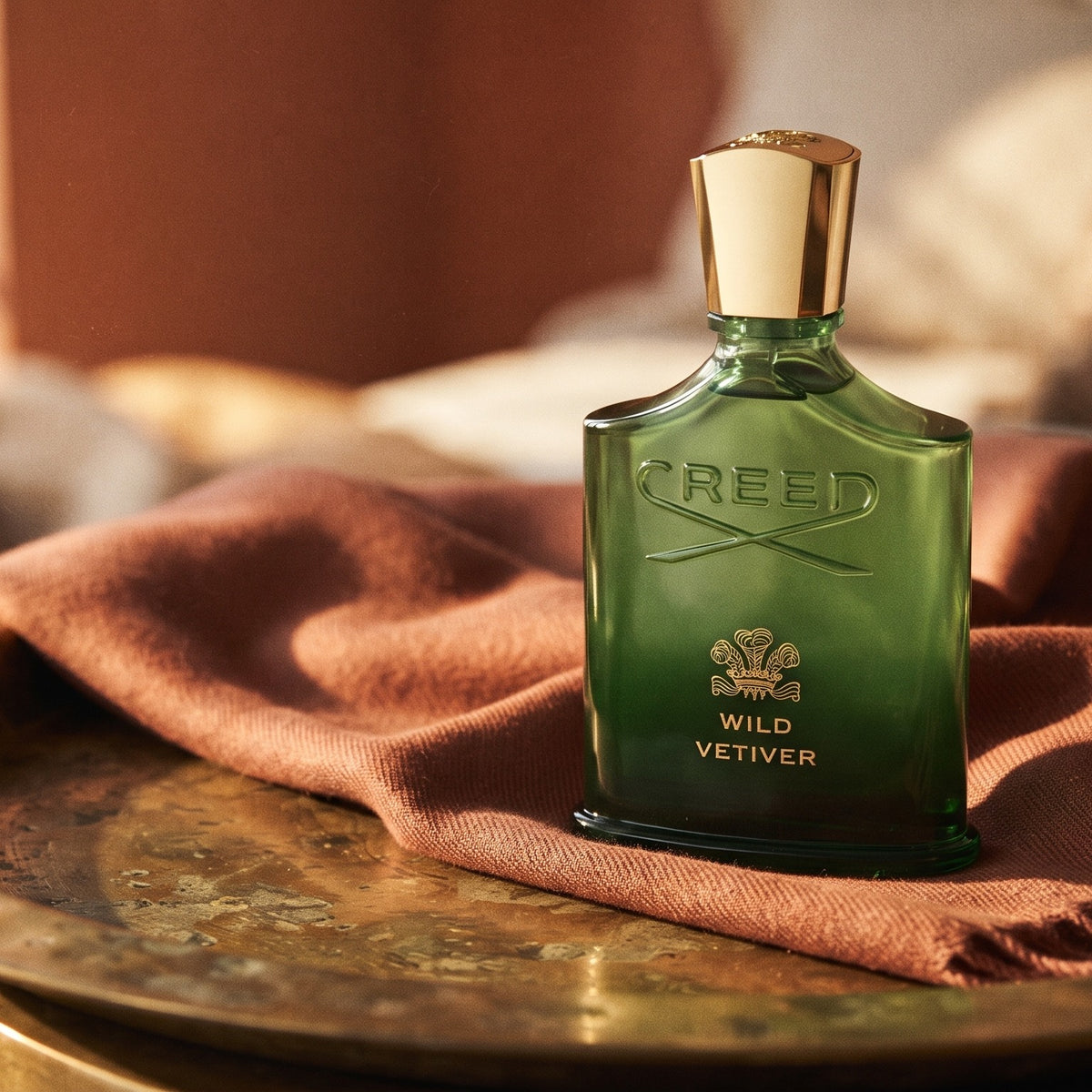 Creed Wild Vetiver EDP on aged brass tray with a folded pashmina in rust tone