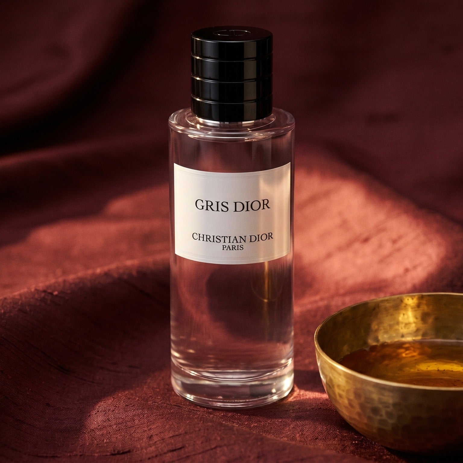 Dior Gris Dior EDP on russet silk with a matte brass bowl holding tonka and amber pieces