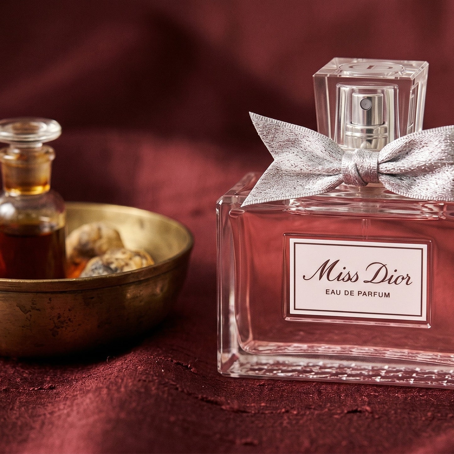 Dior Miss Dior on amber-toned satin with a gold-rim ceramic dish of labdanum