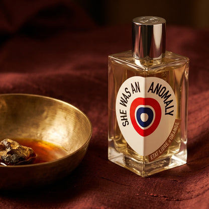 Etat Libre She Was an Anomaly EDP on cinnamon-tone silk with a shallow saucer of warm benzoin resin