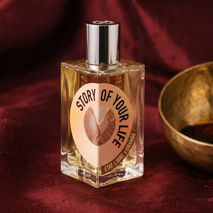 Etat Libre Story of Your Life on raw silk of oxblood color with a brass bowl of ambergris tincture