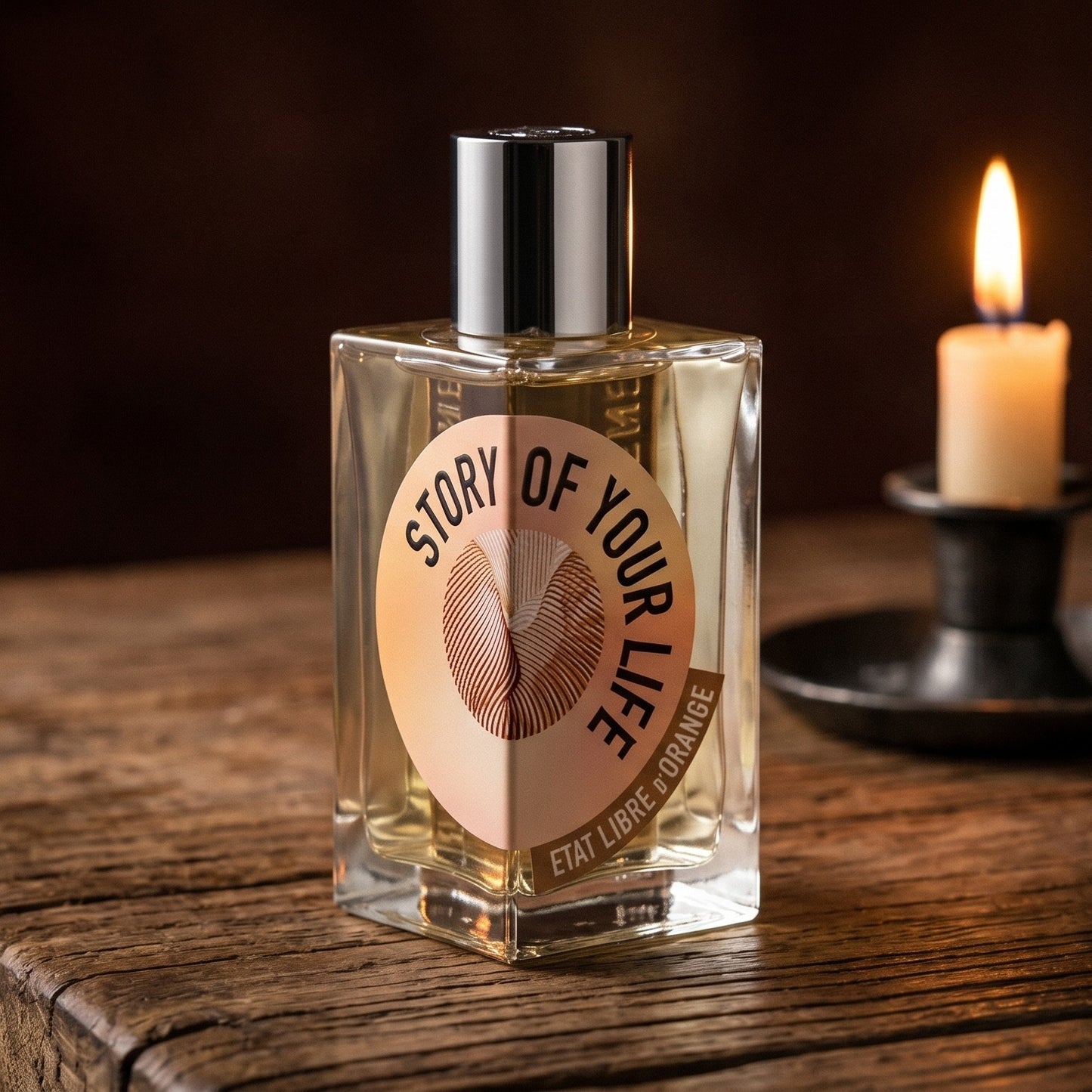 Etat Libre Story of Your Life on reclaimed oak surface with a glass hurricane lamp softly glowing