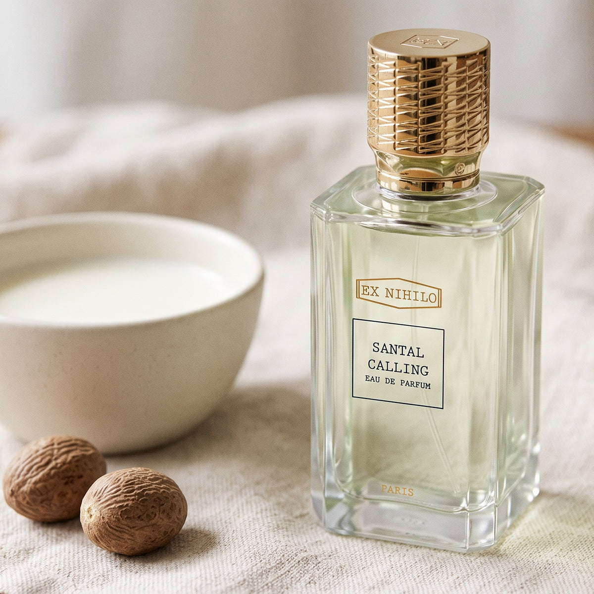 Ex Nihilo Santal Calling EDP on cream linen with a bowl of milk and whole nutmeg