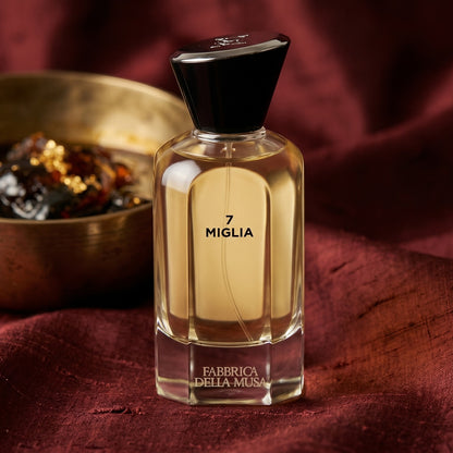Fabbrica Della Musa 7 Migila EDP on raw silk of oxblood color with a brass bowl of ambergris tincture