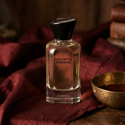 Fabbrica Della Musa Dolcetto Romano EDP on russet silk with a matte brass bowl holding tonka and amber pieces