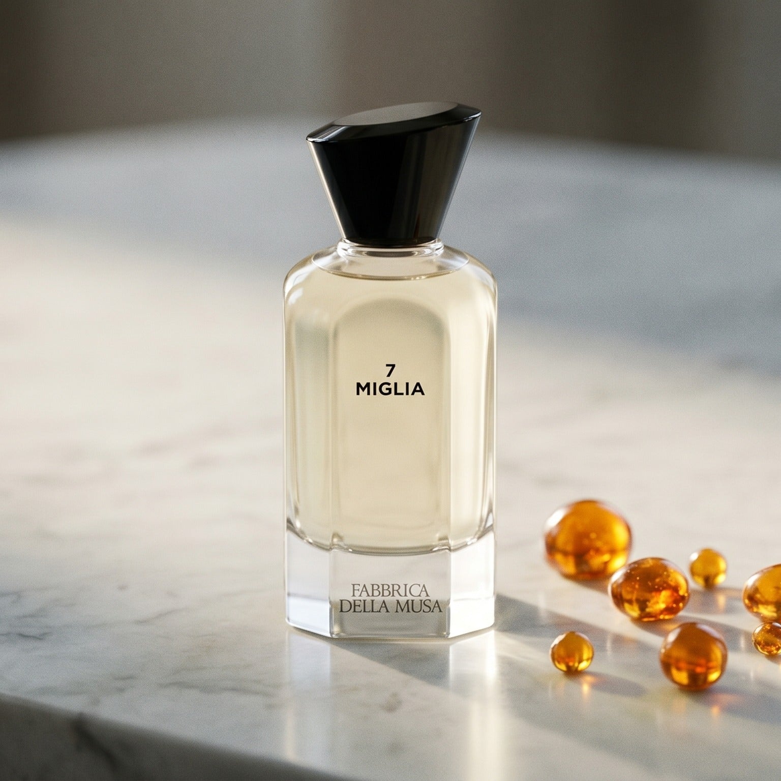 Fabbrica Della Musa Magia Maertrale EDP on pale grey marble with amber resin beads scattered to one side